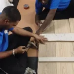 Workers building a wooden crate to protect dining table glass during house shifting in Madurai