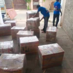 Workers arranging numbered household cartons before loading into a moving truck in Madurai